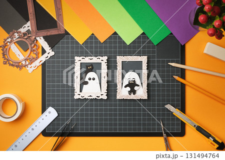 Ready-made handmade paper crafts. Portraits of ghosts with black cats. Nearby are items for paper crafts. 131494764