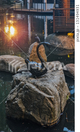 A serene Japanese garden featuring a tranquil lake surrounded by lush greenery and colorful autumn leaves. Sculptures are placed throughout the landscape. A serene Japanese garden featuring a tranquil lake surrounded by lush greenery and colorful autumn leaves. Sculptures are placed throughout the landscape. 131494931