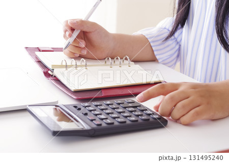 手帳に収支をつけてお金を管理する女性 131495240