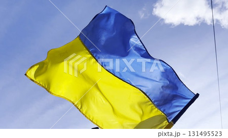 Blue-yellow symbol of Ukraine fluttering at sunny day. Ukrainian flag on flagpole waving at wind against background of sky. Concept of peace and support against russian aggression. Invasion resistance 131495523