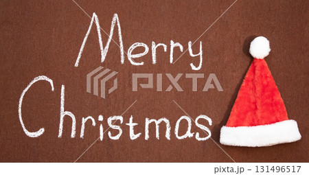 Merry Christmas handwritten in chalk next to Santa's hat 131496517