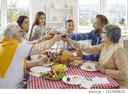 Joyful friendly multigenerational family clinking wine glasses during Thanksgiving celebration. Joyful friendly multigenerational family clinking wine glasses during Thanksgiving celebration. 131498620