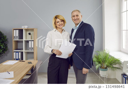 Two smiling business people with paper documents standing in office Two smiling business people with paper documents standing in office 131498641