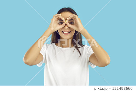Happy beautiful young woman doing binoculars gesture, looking in distance and smiling 131498660