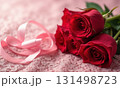 Bouquet of red roses lies on white lace tablecloth with a pink ribbon 131498723