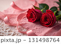 Bouquet of red roses lies on white lace tablecloth with a pink ribbon 131498764