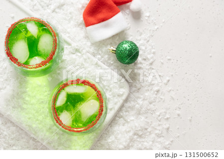 Xmas Green Punch in glass decorated sugar rim on white table make of cool lime sherbet. Tasty drink for Christmas holiday. Rim your festive beverages in red sugar. View from above. Xmas Green Punch in glass decorated sugar rim on white table make of cool lime sherbet. Tasty drink for Christmas holiday. Rim your festive beverages in red sugar. View from above. 131500652
