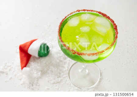 Xmas Green Punch in glass decorated sugar rim on white table make of cool lime sherbet. Christmas beverage for holiday. Rim your festive beverages in red sugar. Close up. 131500654