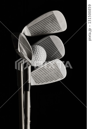 Golf ball with multiple iron clubs stacked against black background Golf ball with multiple iron clubs stacked against black background 131500859