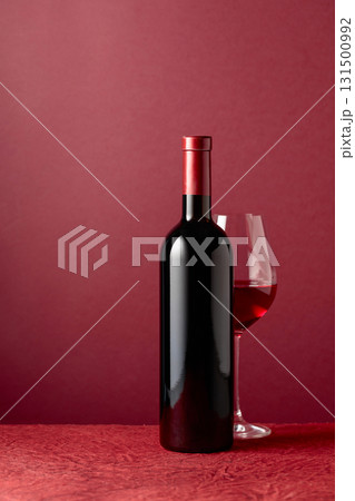 Bottle and glass of red wine on a red background. Bottle and glass of red wine on a red background. 131500992