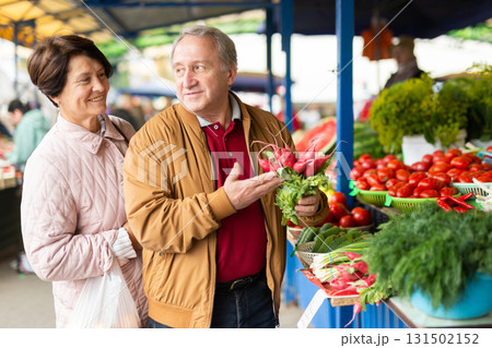 elderly man and woman buy radishes at an open market elderly man and woman buy radishes at an open market 131502152