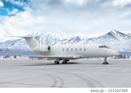 White corporate airplane at winter airport on background of high scenic snow capped mountains White corporate airplane at winter airport on background of high scenic snow capped mountains 131502368