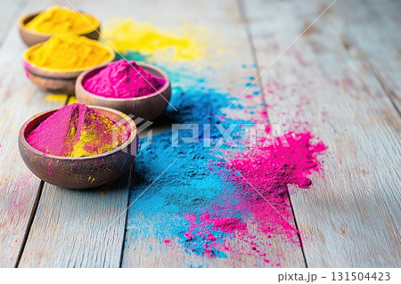 Bowls of colorful Holi powder scattered on wooden surface 131504423