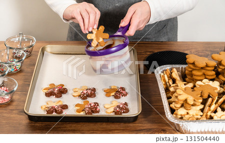 Preparing star-shaped cookies, half-dipped in chocolate, accented with peppermint chocolate chips for the holidays. 131504440