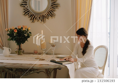 Woman reading book at elegant table with candles Woman reading book at elegant table with candles 131506193