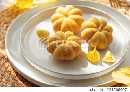 Pumpkin-Shaped Mini Cakes with Cream and Autumn Decor on Woven Placemat Pumpkin-Shaped Mini Cakes with Cream and Autumn Decor on Woven Placemat 131506907