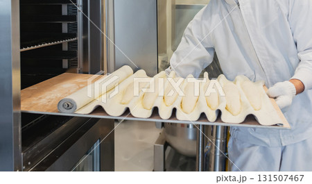 パン職人がバゲット生地をオーブンに入れる作業風景 131507467