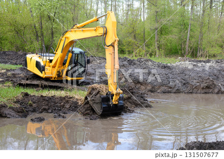 Big powerful excavator digging drainage channel in swamp in countryside 131507677