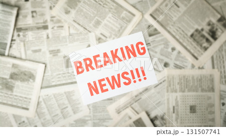Wide picture of blurred newspapers on the table with the red inscription BREAKING NEWS in the middle on white paper 131507741