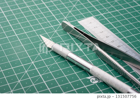 Different stationery equipment on cutting mat. Scalpel, tweezers and ladder on table 131507756