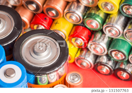 Stack of used batteries on a red background. Background of alkaline battery Stack of used batteries on a red background. Background of alkaline battery 131507763