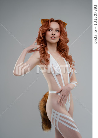 Beauty woman showcasing body art with tape and fur in studio setting 131507893