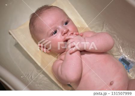 Infant baby boy washed in small bath tub, view from above Infant baby boy washed in small bath tub, view from above 131507999