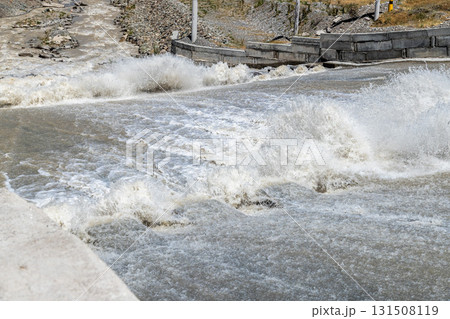 Powerful water splashing against concrete spillway with dentate chutes Powerful water splashing against concrete spillway with dentate chutes 131508119