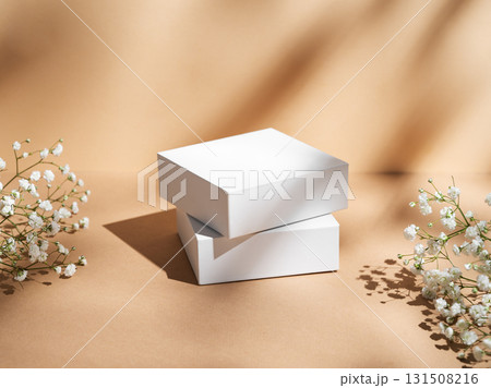 Two white square box on a beige background with gypsophila flowers and soft shadows. Two white square box on a beige background with gypsophila flowers and soft shadows. 131508216