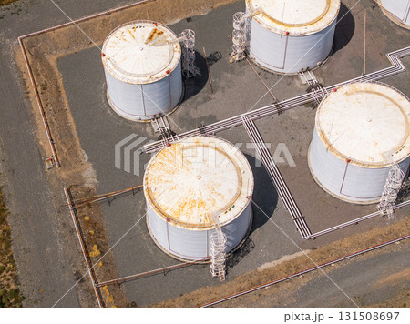 Aerial view of four industrial fuel storage tanks with rust 131508697