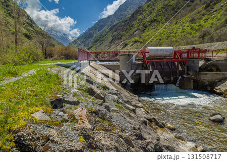 Water control structure with metal gate and red bridge in mountains 131508717