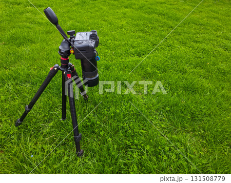 Camera and tripod in serene grassy field during daytime 131508779