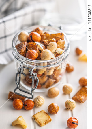 Salted snack. Coated peanuts and mini crackers in jar on white table. Salted snack. Coated peanuts and mini crackers in jar on white table. 131508848