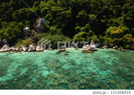 Crystal clear waters offer views of vibrant coral reefs next to lush green jungles on the Perhentian Islands in Malaysia. 131508919