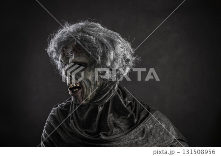 Scary zombie with gray hair over dark background Scary zombie with gray hair over dark background 131508956