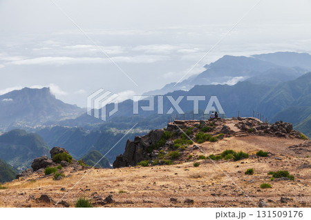 Two hikers rest on a rocky lookout at a mountain summit, Madeira, Portugal 131509176