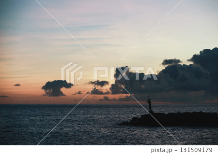 A tranquil coastal scene at dusk features a lone lighthouse on a rocky breakwater, A tranquil coastal scene at dusk features a lone lighthouse on a rocky breakwater, 131509179
