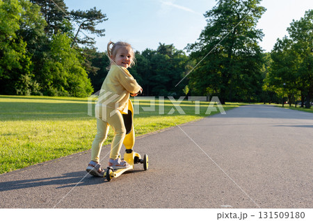 Child riding. Scooter toddler park play. Summer road motion casual sport. 131509180