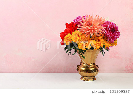 Bouquet of beautiful dahlias and marigolds on an old pink background in grunge style, abstract floral arrangement, spring or autumn background with space for text, minimal holiday concept, discreet 131509587