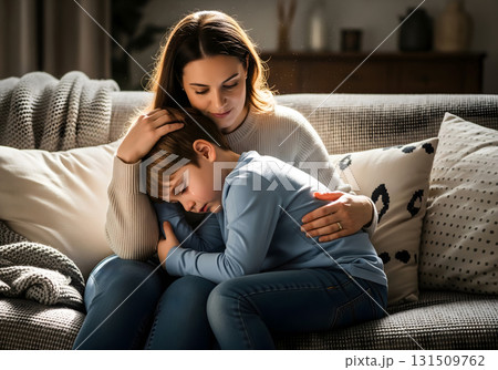 Mother comforts her sad son while sitting on a couch 131509762