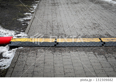 Red Pipe with Yellow Cable Protector on Wet Ground Red Pipe with Yellow Cable Protector on Wet Ground 131509882