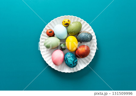 Festive, colorful eggs in various shades are neatly arranged on a decorative plate, symbolizing Easter traditions and spring celebrations with vibrant designs 131509996