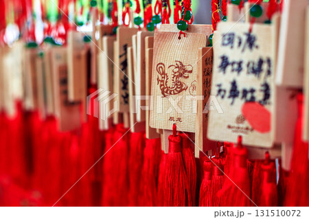 Wooden signs with Chinese characters and dragon designs, decorated with bright red tassels 131510072