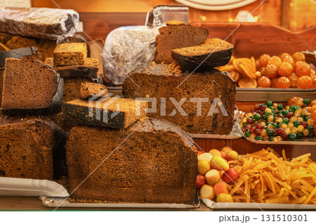 Large slices of traditional fruitcake displayed with candied fruits at Christmas holiday market. Concept of bakery sweetness, fruitcake tradition, festive dessert 131510301