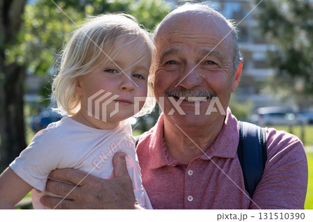 Little blonde girl sitting on grandfather lap, spending happy time together Little blonde girl sitting on grandfather lap, spending happy time together 131510390