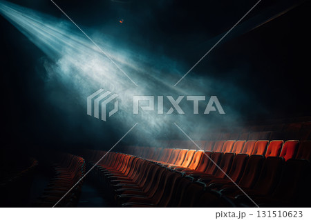 Empty red theater seats illuminated by a bright spotlight through smoke in a dark hall Empty red theater seats illuminated by a bright spotlight through smoke in a dark hall 131510623