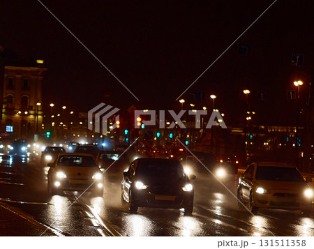 Bright night traffic: blurred car headlights on a wet street in the city center 131511358