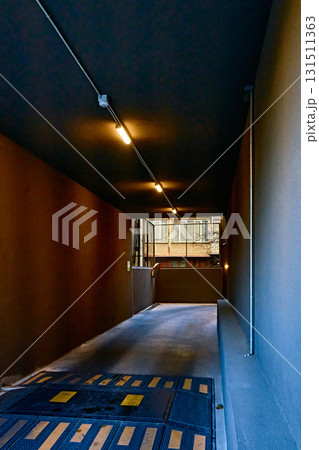 Contrasting narrow entrance to a parking lot or garage with a low black ceiling and yellow lamps Contrasting narrow entrance to a parking lot or garage with a low black ceiling and yellow lamps 131511363