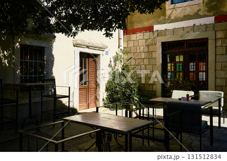 Shaded Mediterranean Cafe Terrace with Historic Stone Walls and Dramatic Sunlight and Shadow Shaded Mediterranean Cafe Terrace with Historic Stone Walls and Dramatic Sunlight and Shadow 131512834
