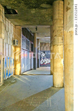 Covered Concrete Walkway with Pillars, Graffiti, and Dramatic Light in an Urban Underpass 131512841